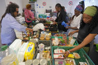 Michelle Dornelly, second right, and various of volunteers prepare food before the Community Food Hub opens in Hackney, London, Thursday, June 13, 2024. Since calling a general election, British Prime Minister Rishi Sunak has been at pains to repeat a key message on the campaign trail: The economy is turning a corner, inflation is down, and things are looking up. That’s not the reality for millions across the U.K. still feeling the squeeze from high food, energy and housing prices. (AP Photo/Kin Cheung)