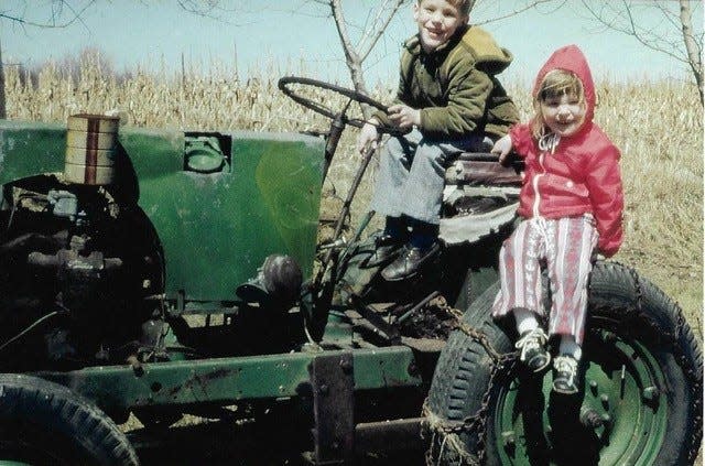 Ingrid Kaat (right) and her brother Dean Kaat (left) ride on a green tractor as kids on their family's farm in Sheboygan Falls.