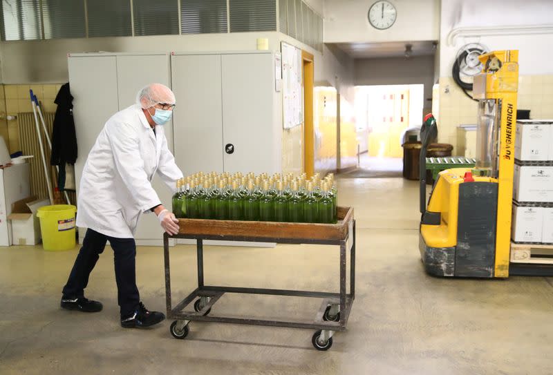 Staff brings bottles of pear and mint alcohol for labelling at Swiss distiller Morand in Martigny