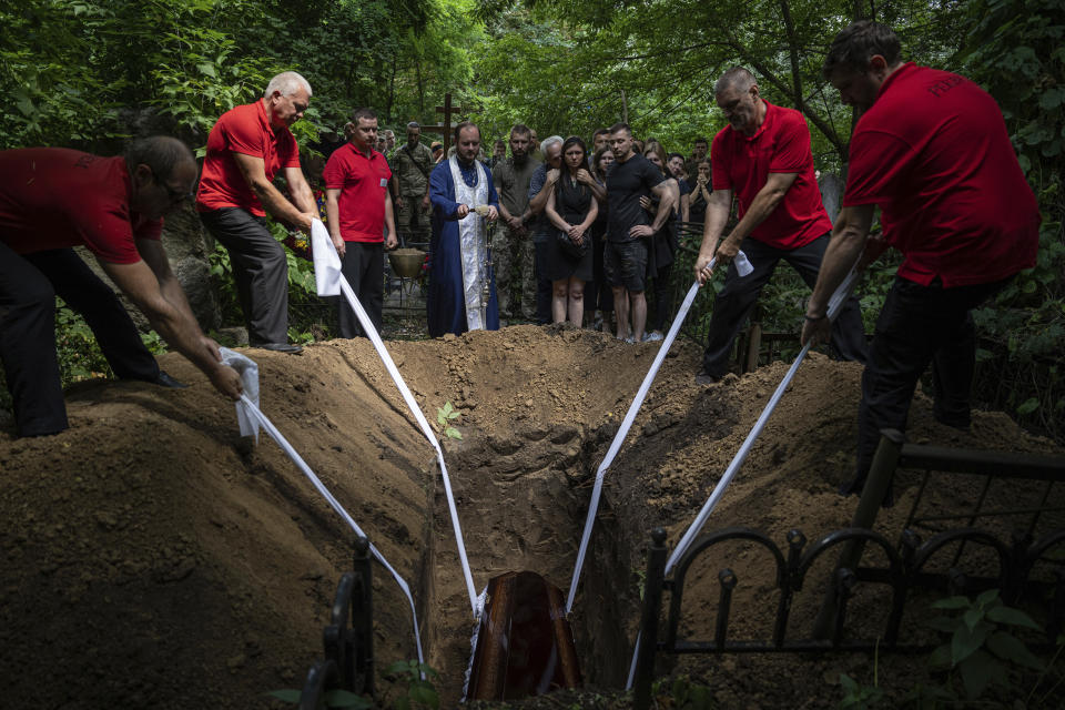 FILE - Funeral workers down the coffin with Ukrainian soldier Andrii Husak aka Lytsar of 47th brigade during a funeral ceremony in Dnipro, Ukraine, Tuesday, July 11, 2023. During the Ukrainian counter-offensive on July 4th in Zaporizhzhia region, Bradley fighting vehicle was hit by a Russian shell, due to which the gunner Husak was seriously injured and lost his legs. On July 7, while being transported to the hospital, Husak's heart stopped. (AP Photo/Evgeniy Maloletka, File)