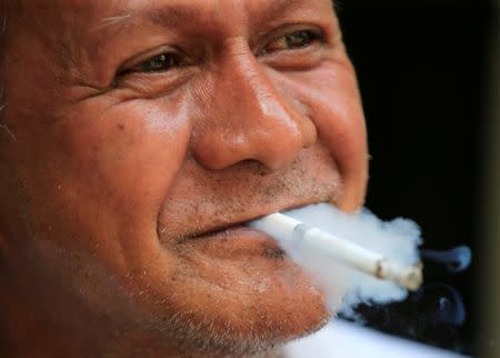 A man smoke cigarette, while taking a break, along a main street in metro Manila, Philippines May 19, 2017. REUTERS/Romeo Ranoco