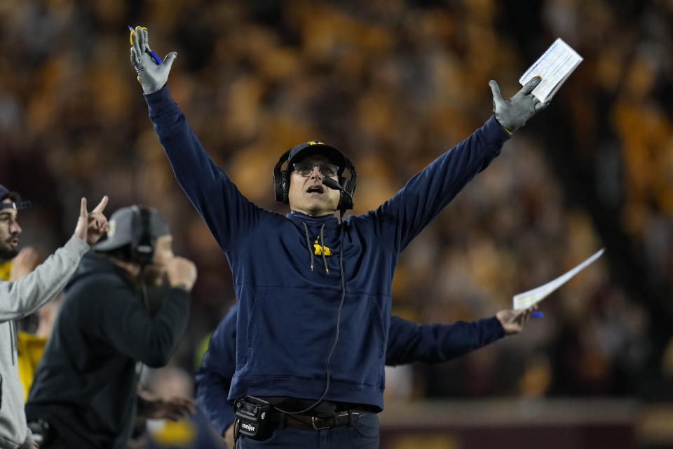 FILE - Michigan head coach Jim Harbaugh signals for a touchdown while looking at the replay board during the first half of an NCAA college football game against Minnesota, Saturday, Oct. 7, 2023, in Minneapolis. When Jim Harbaugh and the University of Michigan have their day in court, trying to at least pause punishment from the Big Ten for a sign-stealing scheme, sports law experts will be among those watching how the extraordinary confrontation plays out. (AP Photo/Abbie Parr, File)