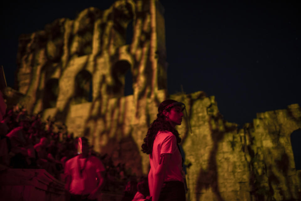 Stewards wearing plastic visors stand at the Odeon of Herodes Atticus in Athens, during a concert on Wednesday, July 15, 2020. Greek Culture Ministry allowed the ancient theaters of Epidaurus in southern Greece and Herodes Atticus in Athens to host performances under strict safety guidelines due the COVID-19 pandemic. (AP Photo/Petros Giannakouris)