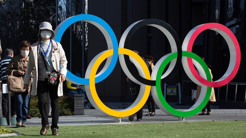 Women with surgical masks, pictured here walking next to the Olympic Rings in front of the Japan Olympic Museum in Shinjuku.