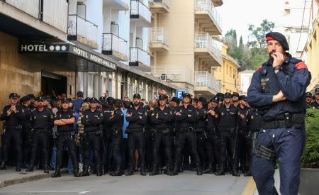 FILE PHOTO - A Mosso d'Esquadra, or Catalan regional police officer, stands in front of a group of Spanish National Police officers who shout at protestors outside their hotel in Pineda de Mar, north of Barcelona, Spain, October 3, 2017. REUTERS/Albert Gea/File Photo