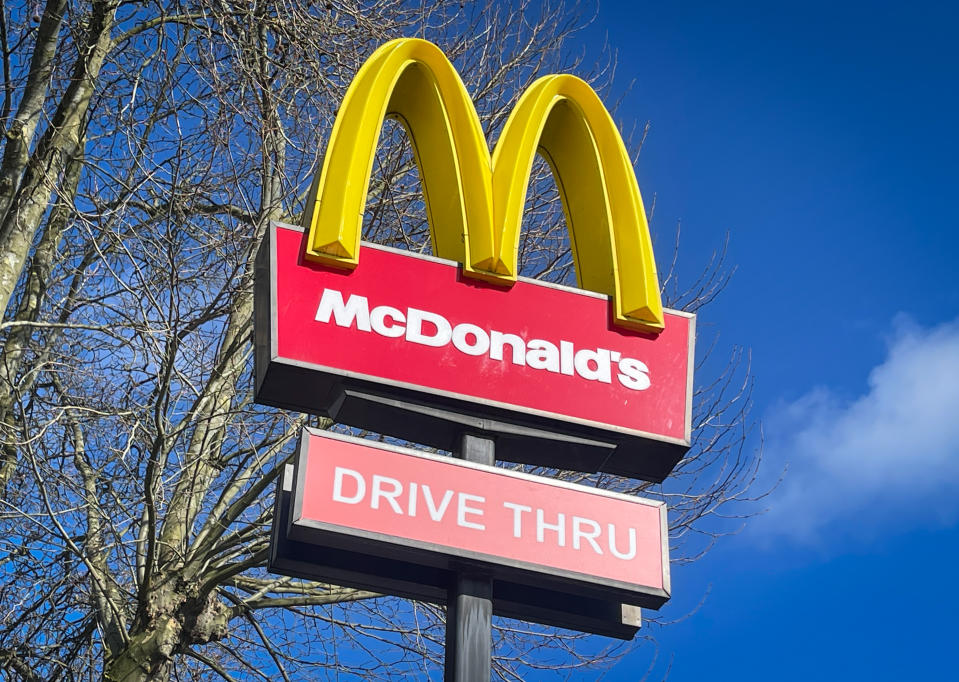 The sun shines on the Golden Arches and Drive Thru logo of the fast food restaurant McDonald's