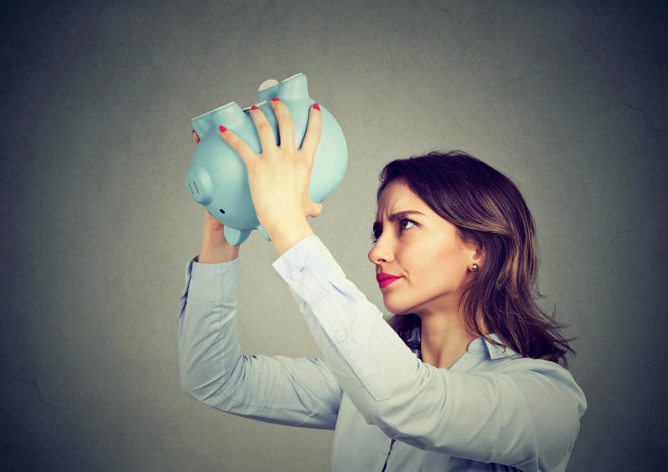 Person shaking an empty piggy bank.