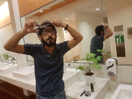 Syrian refugee Hassan Al Kontar tries to give himself a haircut in the bathroom at the Kuala Lumpur International Airport, where he was stranded for seven months, in Kuala Lumpur, Malaysia, August 21, 2018. Courtesy of Hassan Al Kontar/Handout via REUTERS