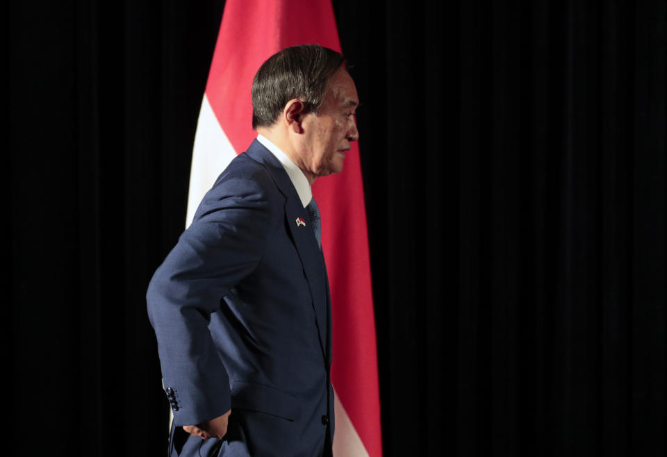 Japanese Prime Minister Yoshihide Suga walks past Indonesian national Red-White flag as he arrives for a press conference in Jakarta, Indonesia, Wednesday, Oct. 21, 2020. Suga is on a four-day visit to Vietnam and Indonesia. (AP Photo/Dita Alangkara, Pool)