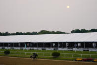 The sun peaks through a thick layer of clouds as Preakness Stakes entrant Blazing Sevens works out ahead of the 148th running of the Preakness Stakes horse race at Pimlico Race Course, Wednesday, May 17, 2023, in Baltimore. (AP Photo/Julio Cortez)