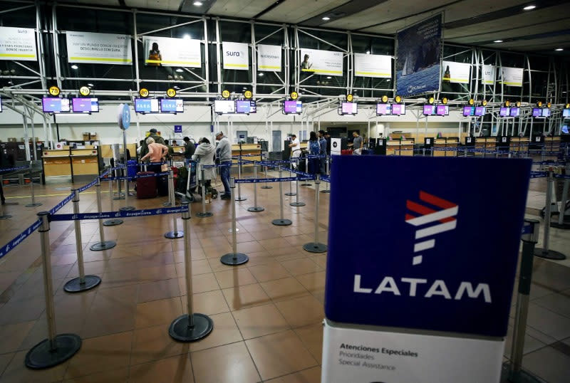 FILE PHOTO: Passengers wait to check in for their flights at the departures area of Latam airlines inside the international airport in Santiago