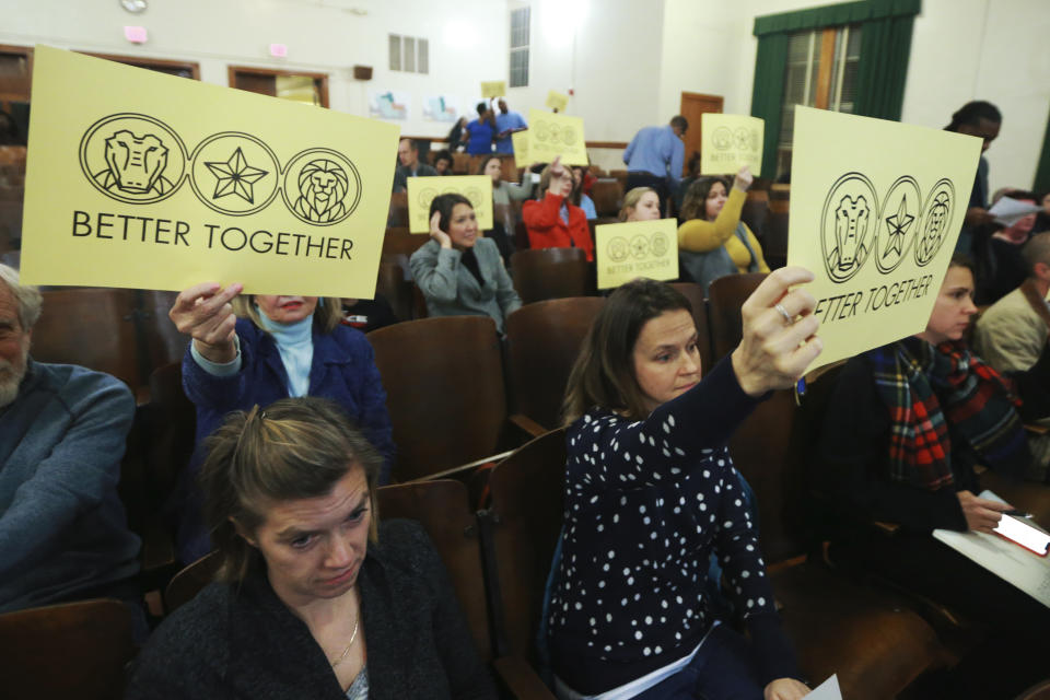 In this Dec. 16, 2019, photo, attendees hold signs during the Richmond School Board's last public hearing on redistricting at Ginter Park Elementary School in Richmond, Va. From New York City to Richmond, sweeping proposals to ease inequities have been scaled back or canceled after encountering a backlash. In Virginia’s capital city, the school board approved a plan that reassigned some students but rejected more sweeping proposals that would have diversified Richmond’s whitest elementary schools. (AP Photo/Steve Helber)