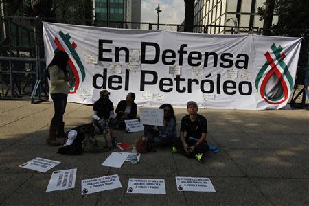 Demonstrators sit in front of a banner reading "In defence of the oil" during a protest against the energy reform bill outside the U.S. Embassy in Mexico City December 9, 2013. REUTERS/Tomas Bravo