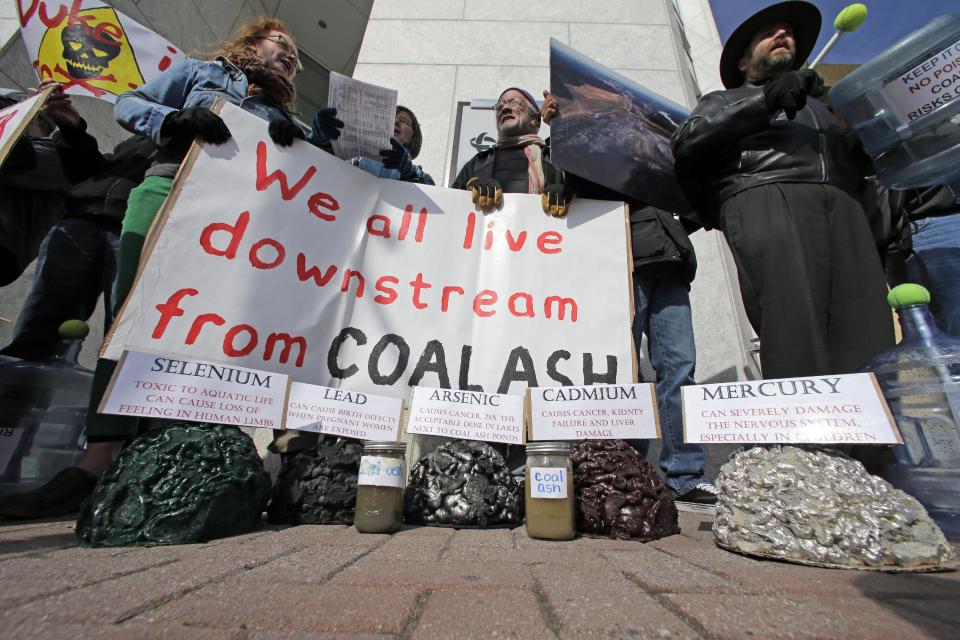 Demonstrators chant and hold signs behind a display of coal ash and the chemicals in it during a protest near Duke Energy's headquarters in Charlotte, N.C., Thursday, Feb. 6, 2014 over Duke Energy's coal plants. Duke Energy estimates that up to 82,000 tons of ash has been released from a break in a 48-inch storm water pipe at the Dan River Power Plant on Sunday. (AP Photo/Chuck Burton)