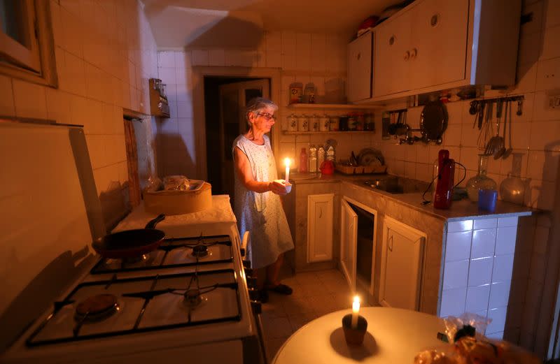 Samira Hanna,70, walks in her kitchen as she holds a candle due to a power cut, in Beirut