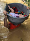 In this photo provided by the Philippine Coast Guard, a baby is carried using a plastic container during rescue operations along a flooded village in the Cagayan valley region, northern Philippines on Friday Nov. 13, 2020. Thick mud and debris coated many villages around the Philippine capital Friday after Typhoon Vamco caused extensive flooding that sent residents fleeing to their roofs and killing dozens of people. (Philippine Coast Guard via AP)