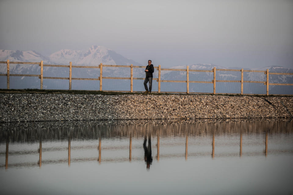 In this image take on Thursday, April 23, 2020 Lorenzo Pasinetti, 53, poses by an artificial lake near his chalet 'Baita Termen', at Monte Pora, near Bergamo, northern Italy. His chalet has a restaurant, a pizzeria a cafe' and an outdoor barbeque, catering for some 2000 people a day in the winter a day and 300 in the summer. After Italy's national lockdown since March 8, he calculated a loss of about 60% compared to the year before. to March last year his loss was about 60%. During the restriction measures he stayed open to provide some 10 families living on the mountain with their groceries. (AP Photo/Luca Bruno)