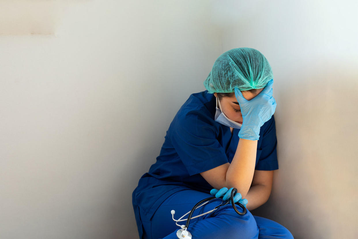 Tired healthcare worker sitting on the floor Getty Images/bymuratdeniz