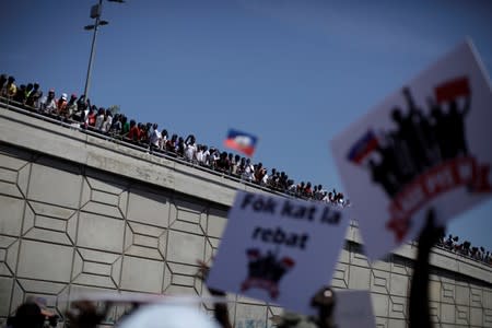 Protesters look from a bridge as other protesters march during a demonstration called by artists to demand the resignation of Haitian president Jovenel Moise, in the streets of Port-au-Prince