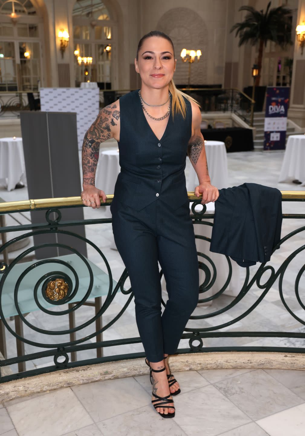 lucy spraggan stands on a balcony overlooking a hotel reception area at an awards ceremony