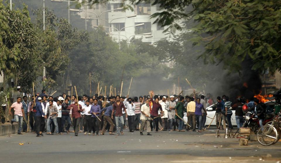 Bangladesh's Jamaat-e-Islami party activists raise their sticks as they approach police during a clash in Dhaka