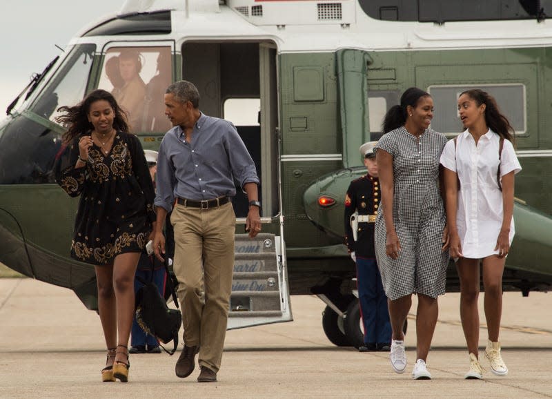 TOPSHOT - US President Barack Obama, First Lady Michelle Obama and daughters Malia and Sasha walk to board Air Force One at Cape Cod Air Force Station in Massachusetts on August 21, 2016 as they depart for Washington after a two-week holiday at nearby Martha’s Vineyard. 