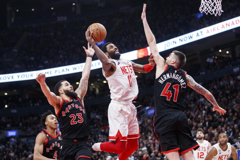 Brooklyn Nets guard Kyrie Irving (11) drives to the net between Toronto Raptors guard Fred VanVleet (23) and forward Juancho Hernangomez (41) during the second half of an NBA basketball game in Toronto, Friday, Dec. 16, 2022. (Cole Burston/The Canadian Press via AP)