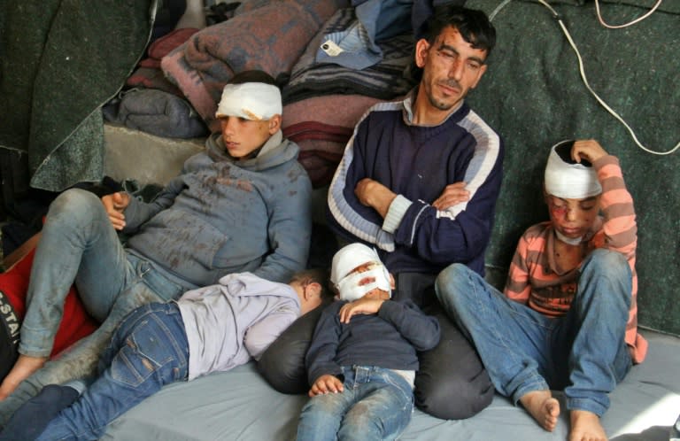 Syrians, who were wounded in a suicide car bombing that hit buses carrying evacuees from besieged government-held towns, sit in a tent on the Syrian-Turkish border on April 17, 2017