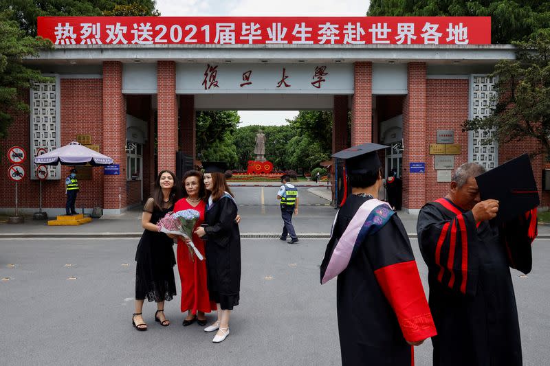 FILE PHOTO: Students take graduation photo in front of the statue of Chinese leader Mao Zedong and a signboard marking the 100th founding anniversary of the Communist Party of China, at Fudan University in Shanghai