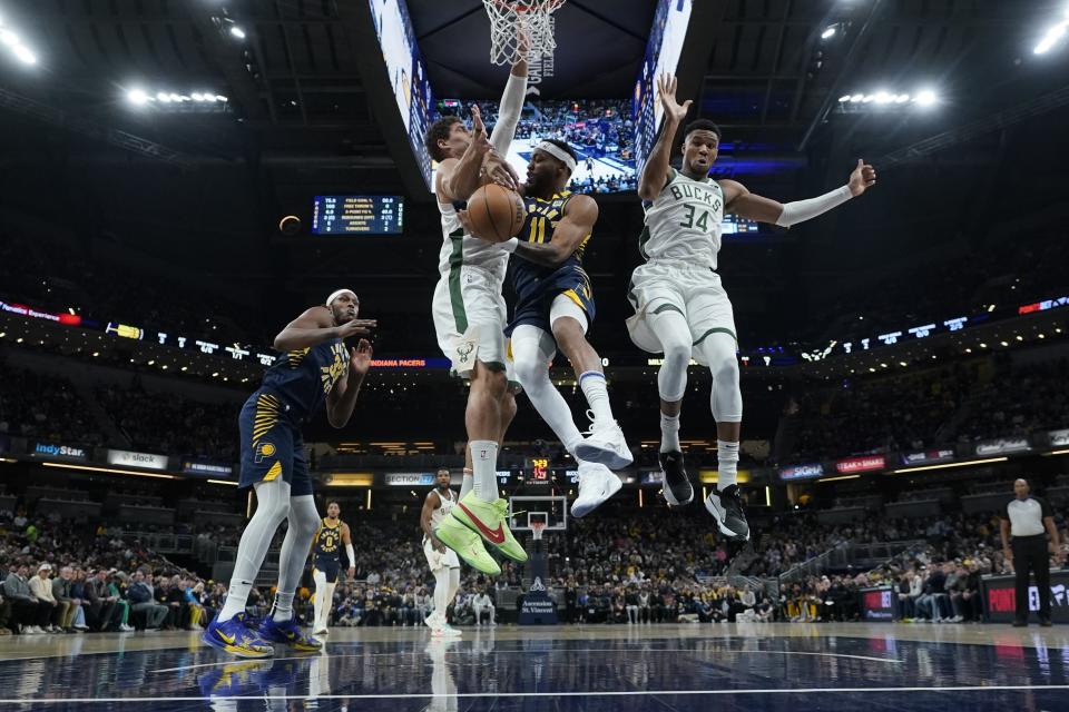 Indiana Pacers' Bruce Brown (11) makes a pass against Milwaukee Bucks' Brook Lopez (11) and Giannis Antetokounmpo (34) during the first half of an NBA basketball game, Wednesday, Jan. 3, 2024, in Indianapolis. (AP Photo/Darron Cummings)