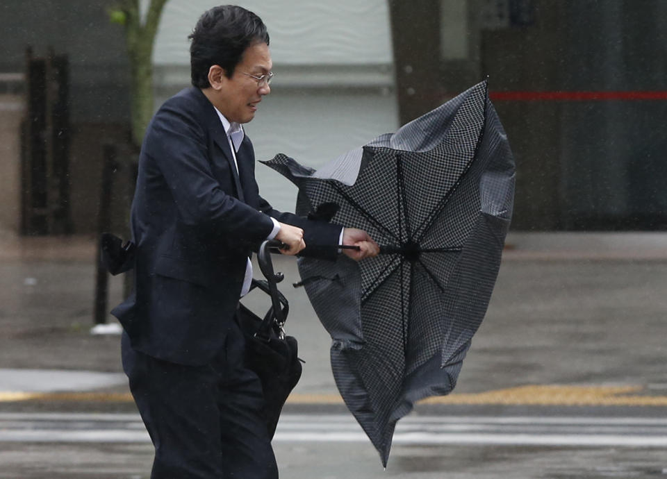 A man struggles against strong wind and rain caused by approaching Typhoon Wipha at a business district in Tokyo October 16, 2013. A once-in-a-decade typhoon threatened Japan on Tuesday, disrupting travel and shipping and forcing precautions to be taken at the wrecked Fukushima nuclear power plant. (REUTERS/Toru Hanai)