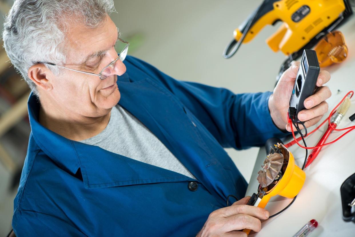 senior adult electrician using digital voltmeter