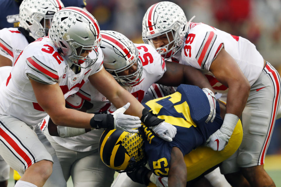 Ohio State linebackers Tuf Borland (32), Davon Hamilton (53) and Malik Harrison (39) smother Michigan running back Hassan Haskins (25) in the second half of an NCAA college football game in Ann Arbor, Mich., Saturday, Nov. 30, 2019. (AP Photo/Paul Sancya)