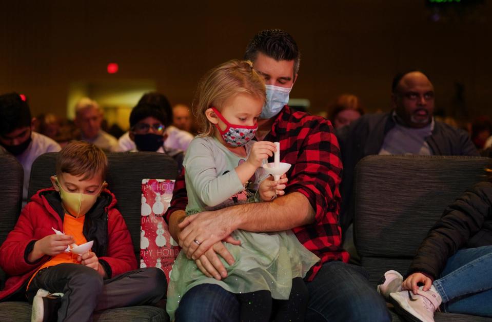 David Stotera of Bloomfield Township holds his daughter Naomi Stotera while sitting with his son Owen (left) during a Christmas Eve church service at Kensington Church in Lake Orion on December 24, 2021.