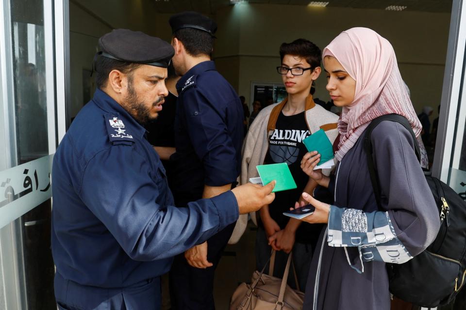 一名警察11月1日在拉法關卡查驗一名巴勒斯坦女子持有的外國護照。路透社