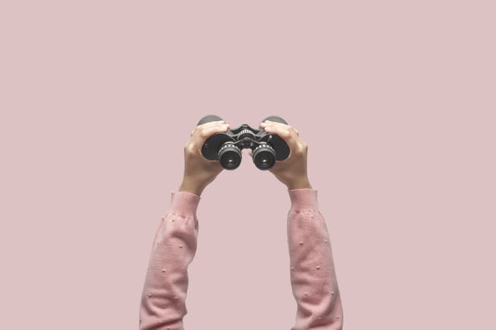 A pair of hands holding up binoculars.