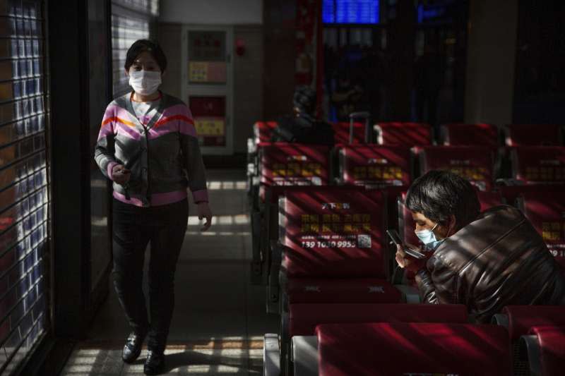 武漢肺炎疫情持續蔓延，北京火車站內的旅客配戴口罩（AP）