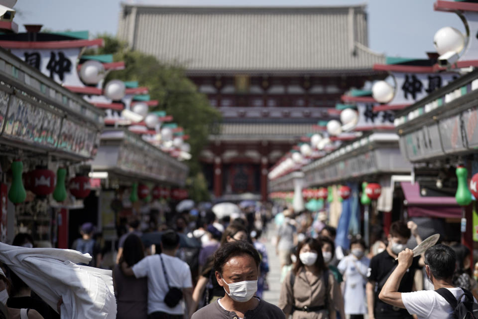 Visitors wearing protective masks to help curb the spread of the coronavirus walk at shopping arcade at in Asakusa district Friday, Aug. 14, 2020, in Tokyo. The Japanese capital confirmed more than 380 coronavirus cases on Friday. (AP Photo/Eugene Hoshiko)