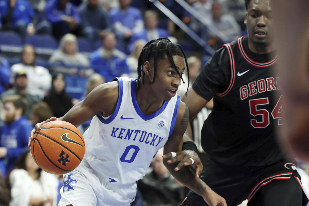 Kentucky's Rob Dillingham (0) drives while defended by Georgia's Russel Tchewa during the second half of an NCAA college basketball game Saturday, Jan. 20, 2024, in Lexington, Ky. Kentucky won 105-96. (AP Photo/James Crisp)