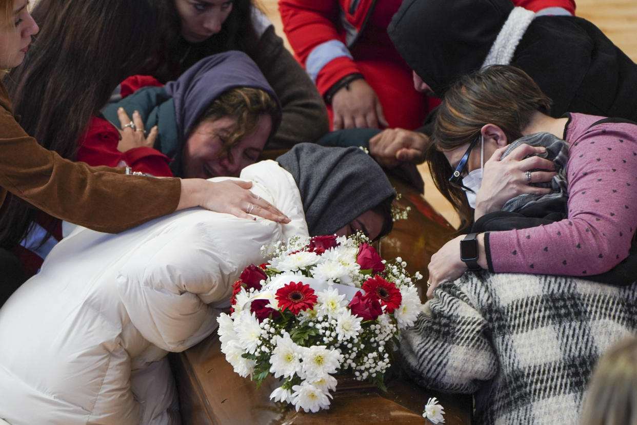 Relatives cry on the coffin of one of the victims of last Sunday's shipwreck at the local sports hall in Crotone, southern Italy, Wednesday, March 1, 2023. Nearly 70 people died in last week's shipwreck on Italy's Calabrian coast. The tragedy highlighted a lesser-known migration route from Turkey to Italy for which smugglers charge around 8,000 euros per person. (Antonino Durso/Lapresse via AP, File)