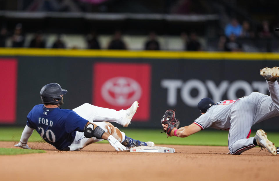 Seattle Mariners' Mike Ford slides into second base for a double ahead of the tag from Minnesota Twins second baseman Kyle Farmer, right, during the seventh inning of a baseball game Tuesday, July 18, 2023, in Seattle. (AP Photo/Lindsey Wasson)