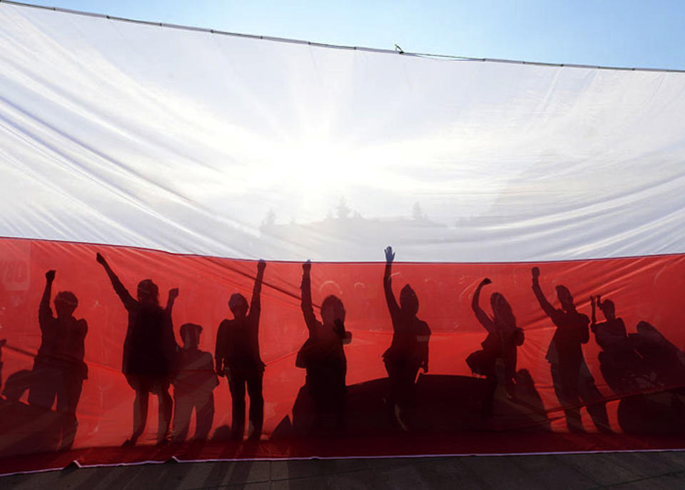 People demonstrate behind a flag in Poland