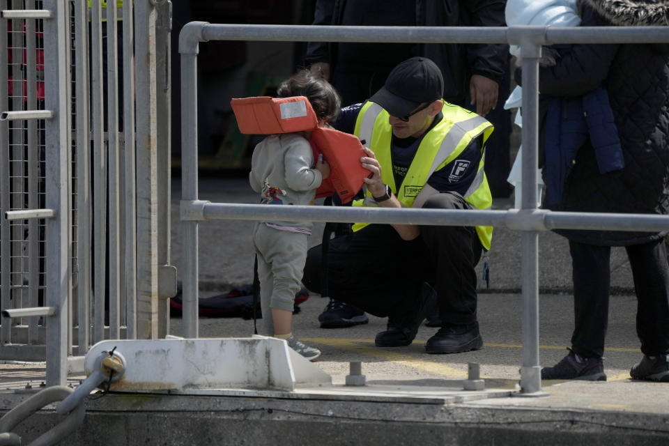 A child is helped to remove a bouyancy aid after arriving with adults thought to be migrants who undertook the crossing from France in small boats and were picked up in the Channel, following their disembarkation from a British border force vessel, in Dover, south east England, Friday, June 17, 2022. The British government vowed Wednesday to organize more flights to deport asylum-seekers from around the world to Rwanda, after a last-minute court judgment grounded the first plane due to take off under the contentious policy. (AP Photo/Matt Dunham)