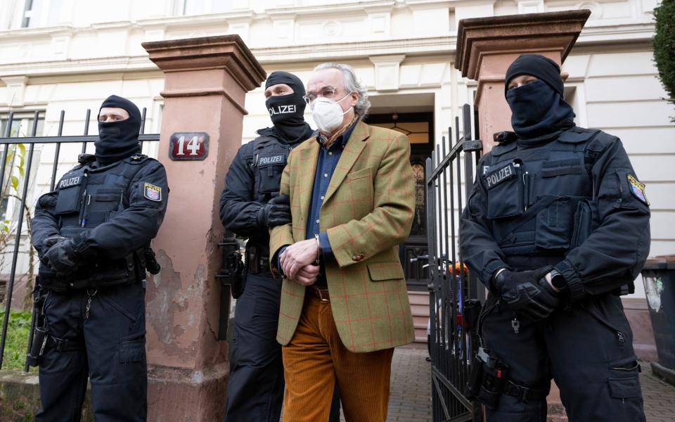 Masked police officers lead Heinrich XIII Prince Reuss, front center, to a police vehicle during a raid against so-called 'Reich citizens' in Frankfurt - Boris Roessler/dpa via AP