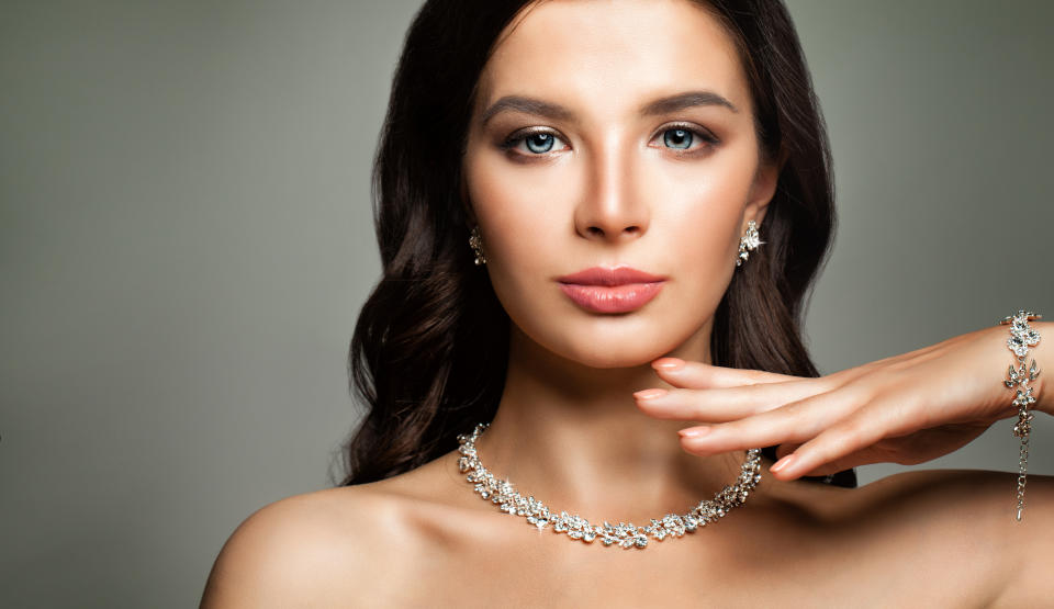 A woman wearing diamond earrings, necklace, and bracelet.