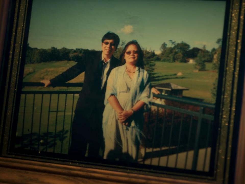 hann pan and bich pan seen in a photo, displayed in a frame on a table. the two are standing in front of a green field, leaning against a railing, and smiling.