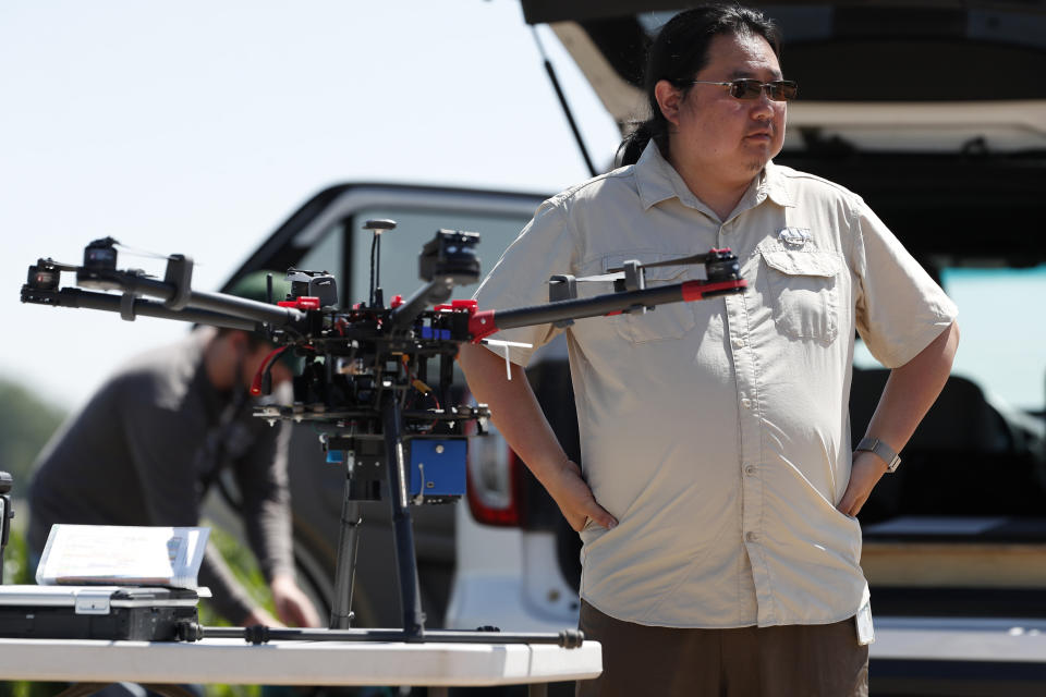 In this Thursday, July 11, 2019, photograph, United States Department of Agriculture engineering technician Kevin Yemoto prepares a drone for flight at a research farm northeast of Greeley, Colo. Researchers are using drones carrying imaging cameras over the fields in conjunction with stationary sensors connected to the internet to chart the growth of crops in an effort to integrate new technology into the age-old skill of farming. (AP Photo/David Zalubowski)