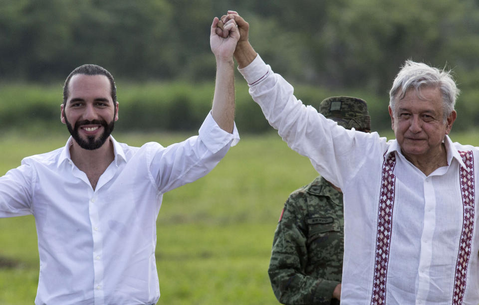 Mexican President Andres Manuel Lopez Obrador, right, and the President of El Salvador Nayib Bukele, raise their arms during a visit to a tree nursery at a military reserve in Tapachula, Mexico, Thursday, June 20, 2019. The presidents met to discuss a development plan that aims to slow a surge of mostly Central American migrants toward the U.S. border. (AP Photo/Oliver de Ros)