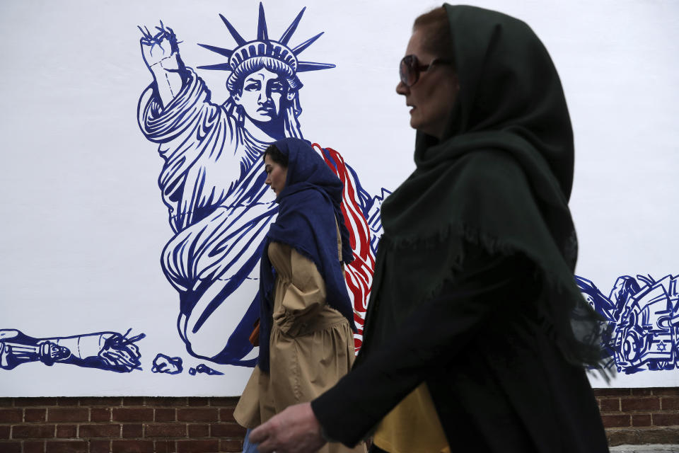People walk past a satirical drawing of Statue of Liberty after new anti-U.S. murals on the walls of former U.S. embassy unveiled in a ceremony in Tehran, Iran, Saturday, Nov. 2, 2019. Anti-U.S. works of graphics is the main theme of the wall murals painted by a team of artists ahead of the 40th anniversary of the takeover of the U.S. diplomatic post by revolutionary students. (AP Photo/Vahid Salemi)