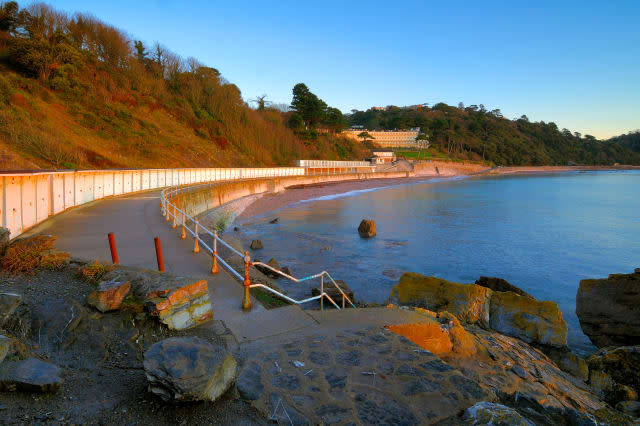 Looking along the promenade of Meadfoot Beach in Torquay in South Devon England at sunrise